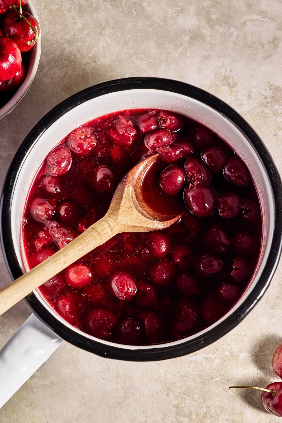 cooking cherries in a small saucepan with a wooden spoon