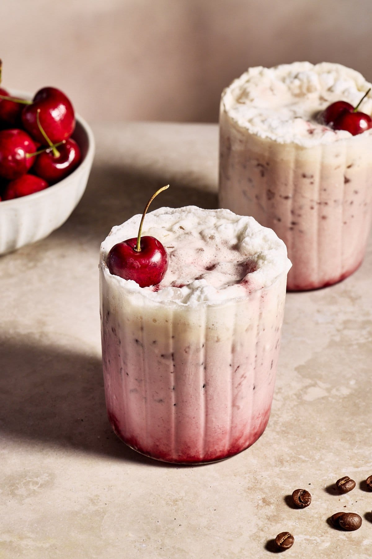 a cherry vanilla latte in a glass topped with a fresh cherry 