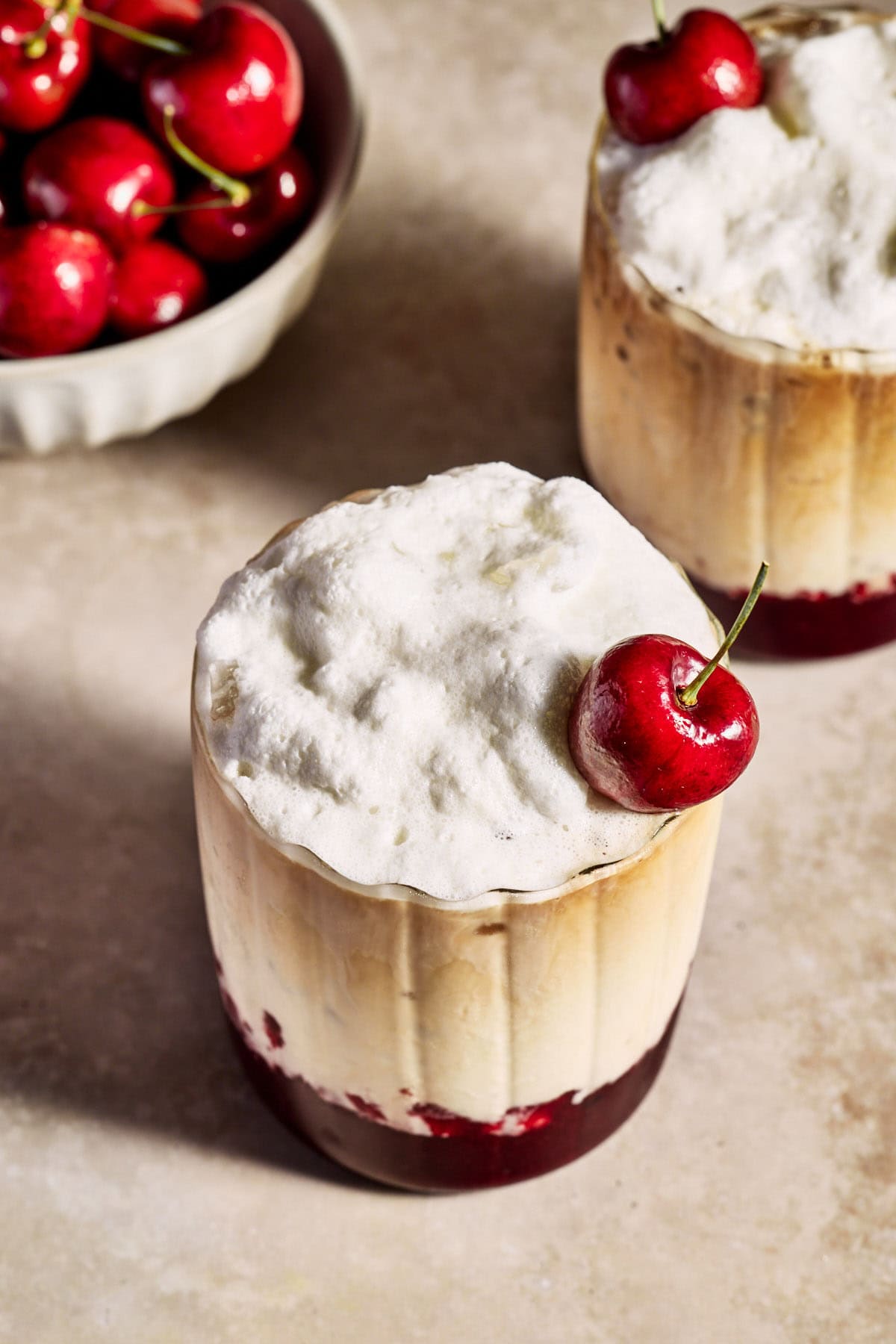 a cherry vanilla latte topped with frothy milk and a cherry