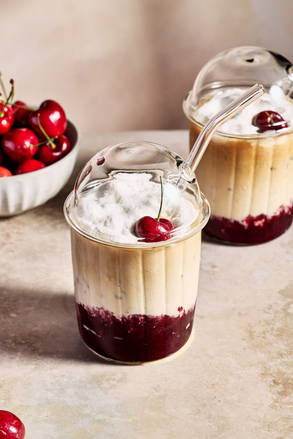 a cherry vanilla latte in a glass topped with whipped cream and a cherry