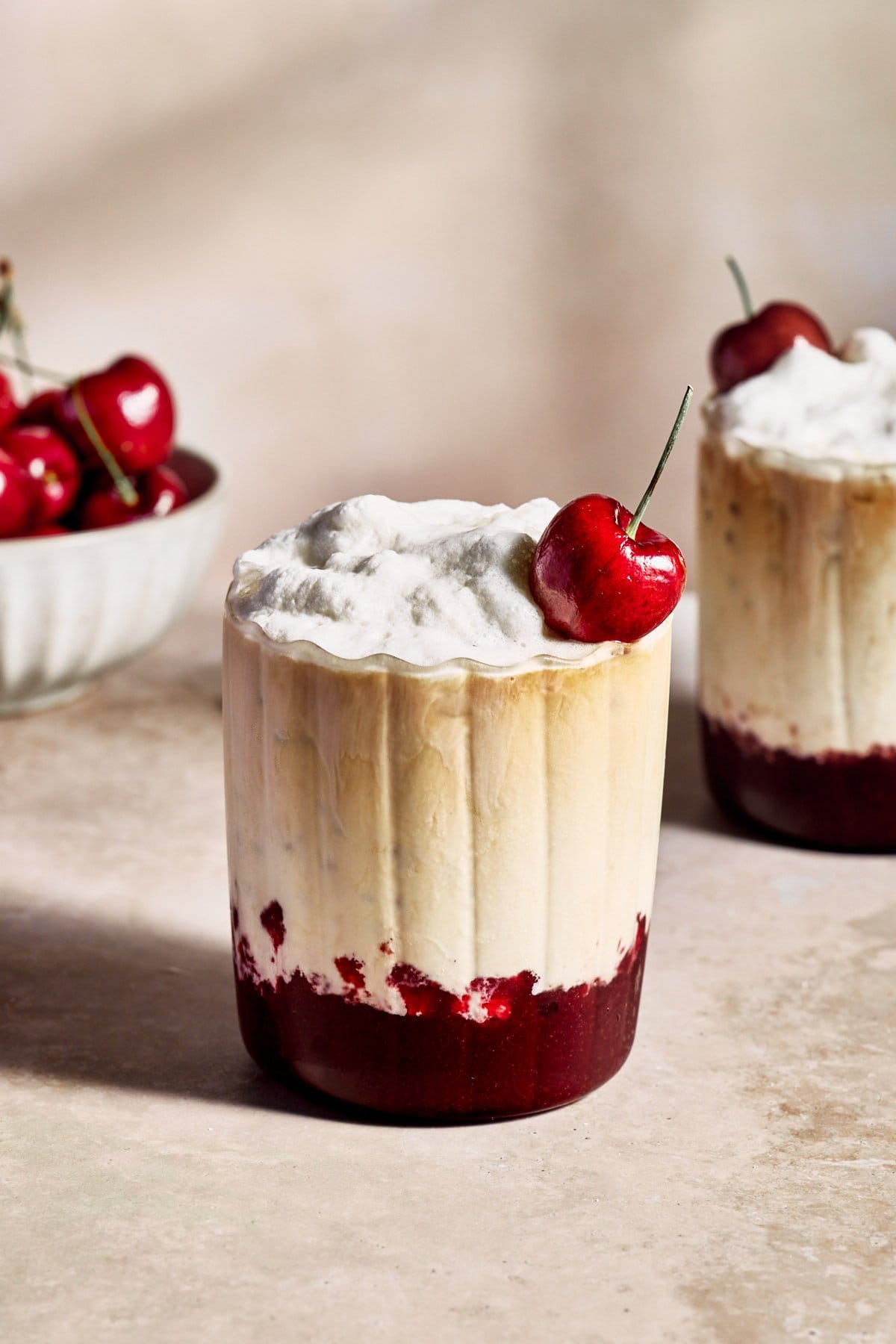 cherry vanilla latte in a glass with whipped cream and topped with a cherry