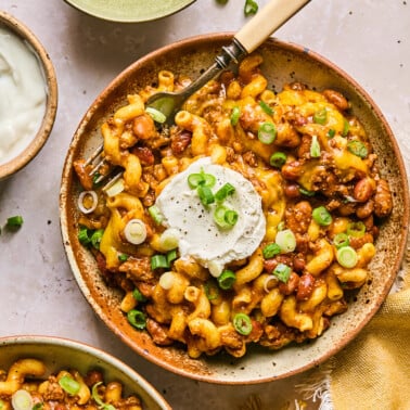 a bowl of Cheesy leftover chili mac with pasta and green onion garnish.