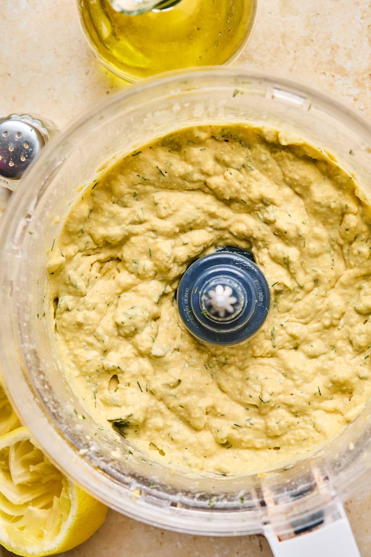 blended ingredients in a food processor making a combined dill pickle hummus. 