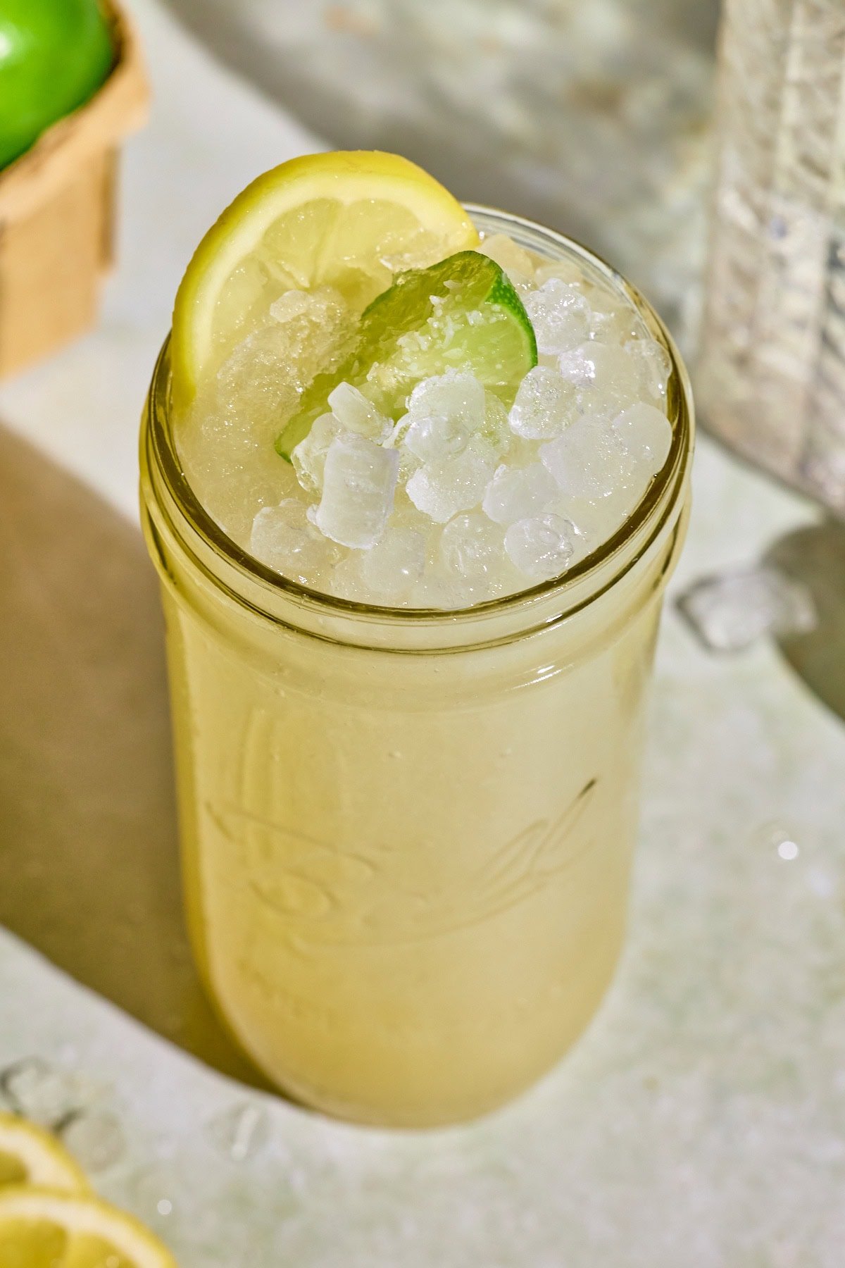 Close-up of a chilled glass of lemon lime Gatorade-style drink with visible citrus slices and a golden green tint.