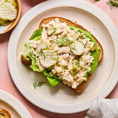 dill pickle chicken salad spread on top of a piece of bread with butter lettuce