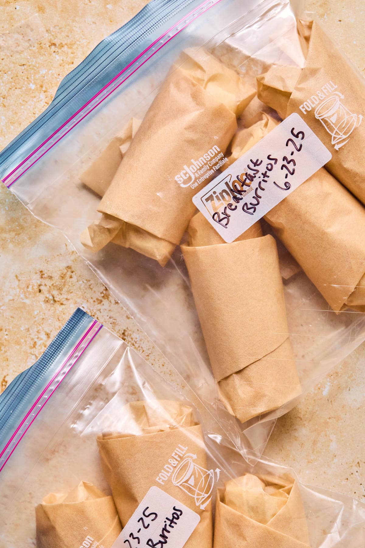 Breakfast burritos wrapped in parchment paper in a freezer bag.