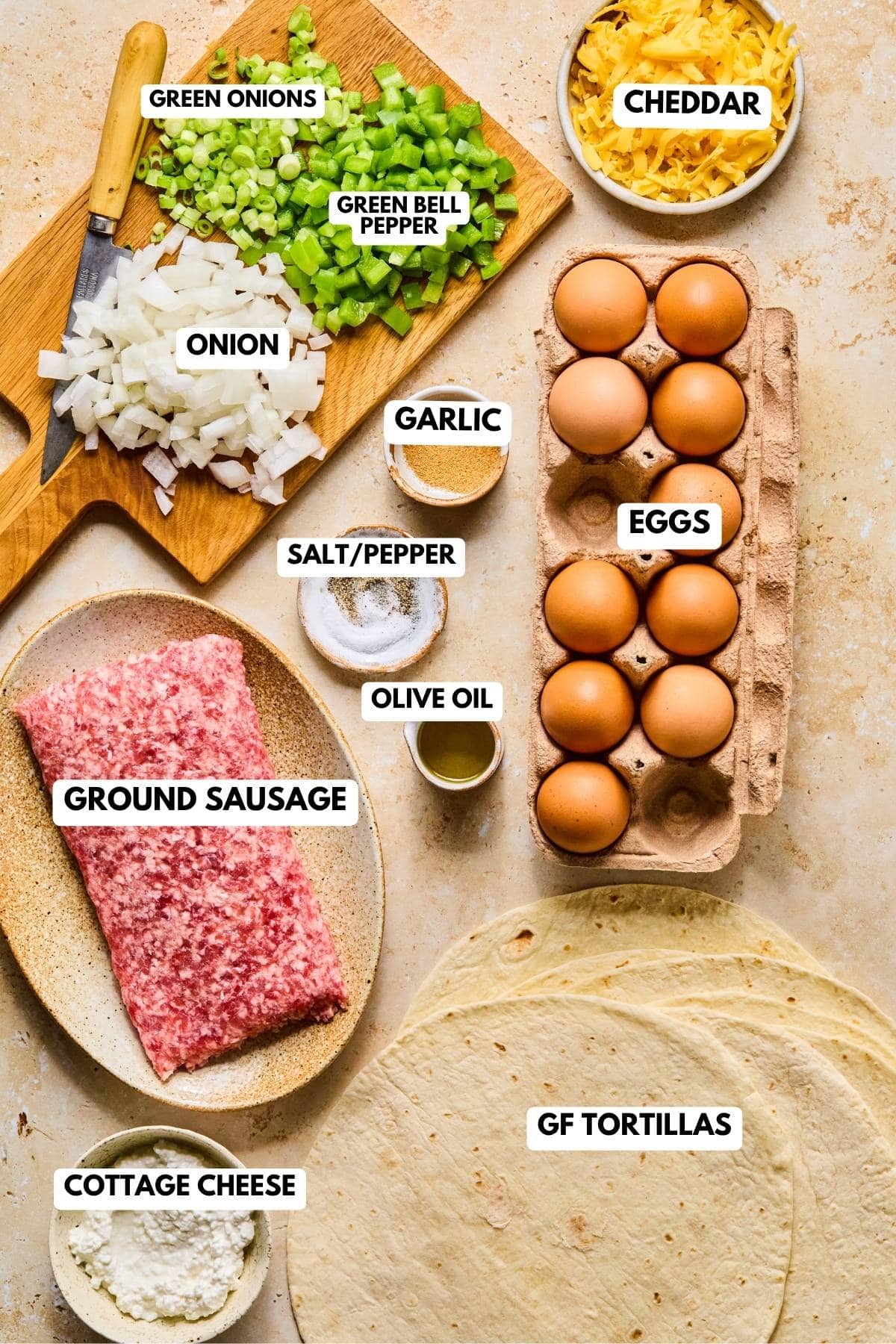 Ingredients for meal prep breakfast burritos showing eggs, sausage, bell pepper, onion, cheese, tortillas, cottage cheese, and seasonings on a light colored background.
