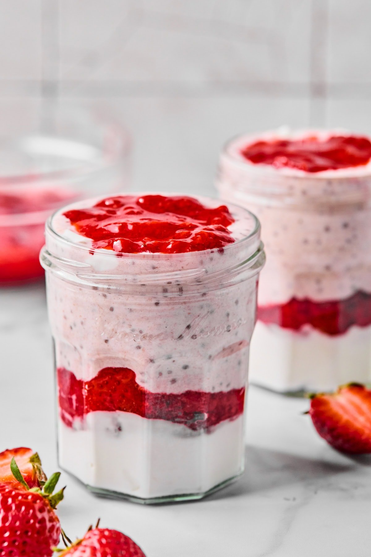 Finished layered strawberry high protein overnight oats topped with fresh strawberries, ready to chill overnight.
