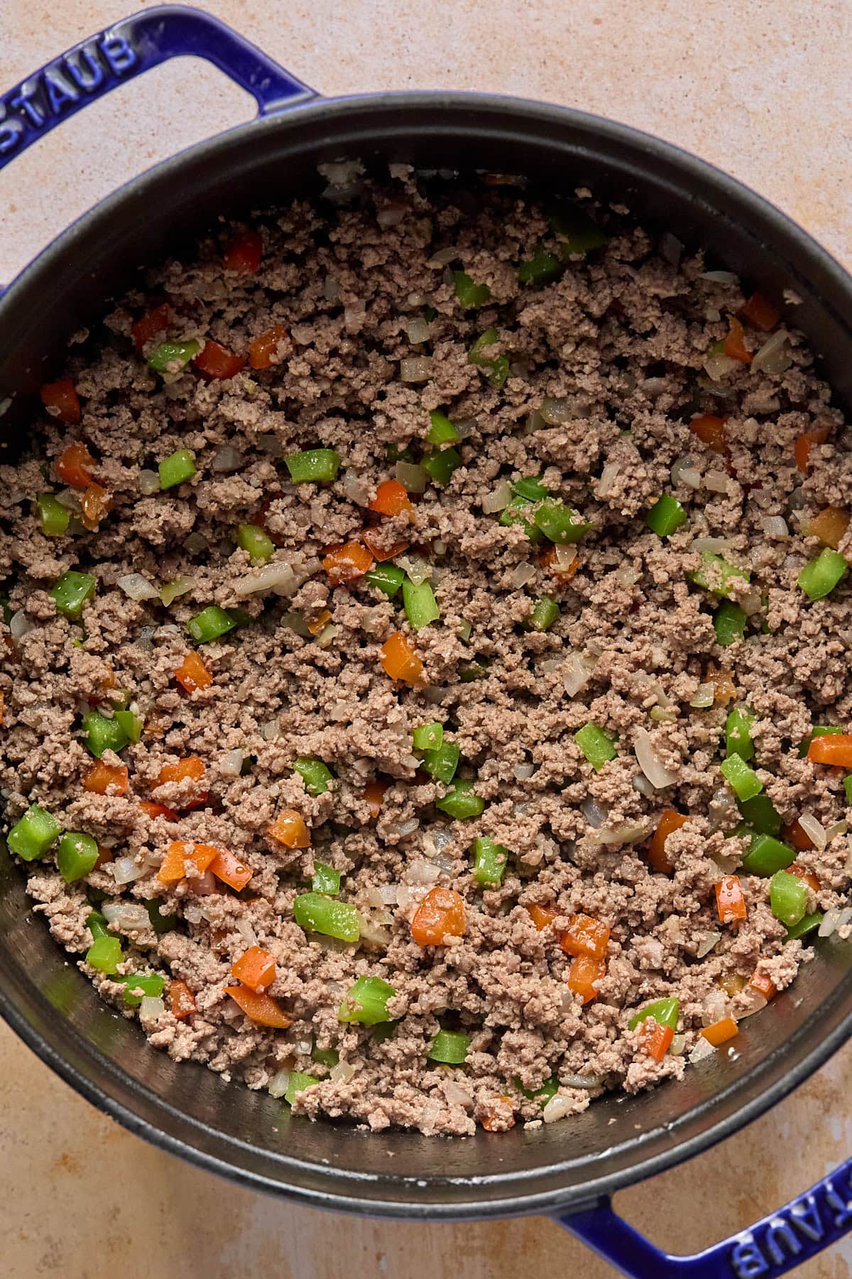 Ground beef browning with sautéed aromatics in a large STAUS pot.