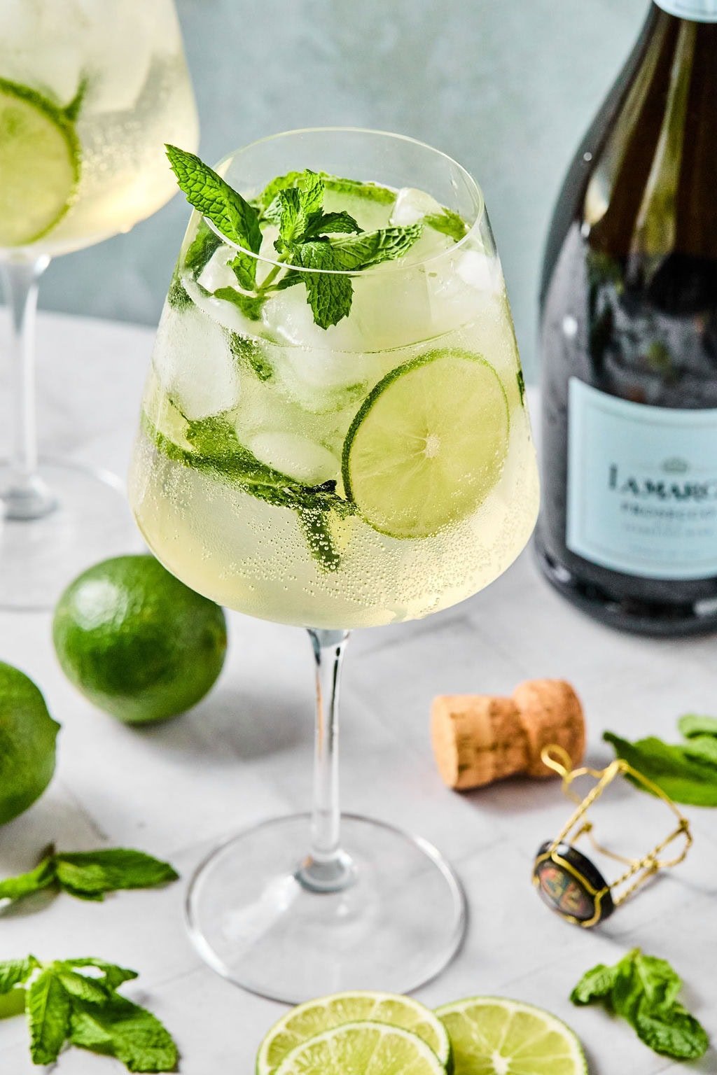 Close-up of a chilled Hugo Spritz with mint and lime, crisp bubbles visible in the glass.