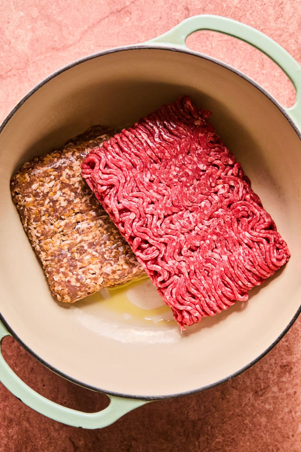 Oil in a Dutch oven with ground beef and Italian sausage.