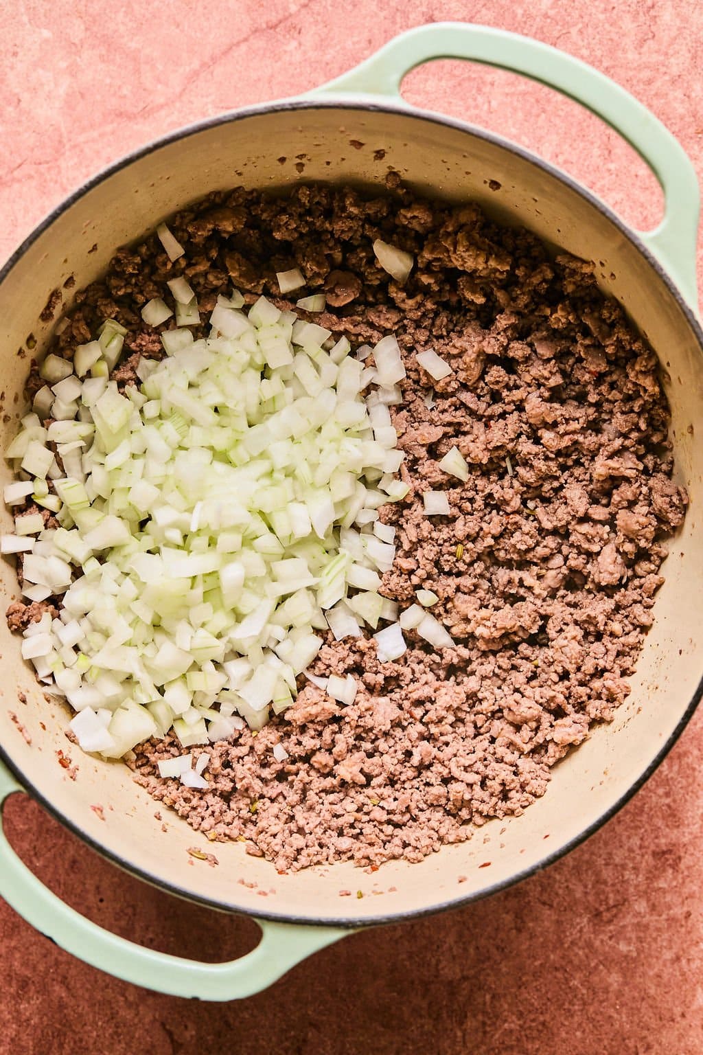Onion added to Dutch oven with browned Italian sausage and ground beef.