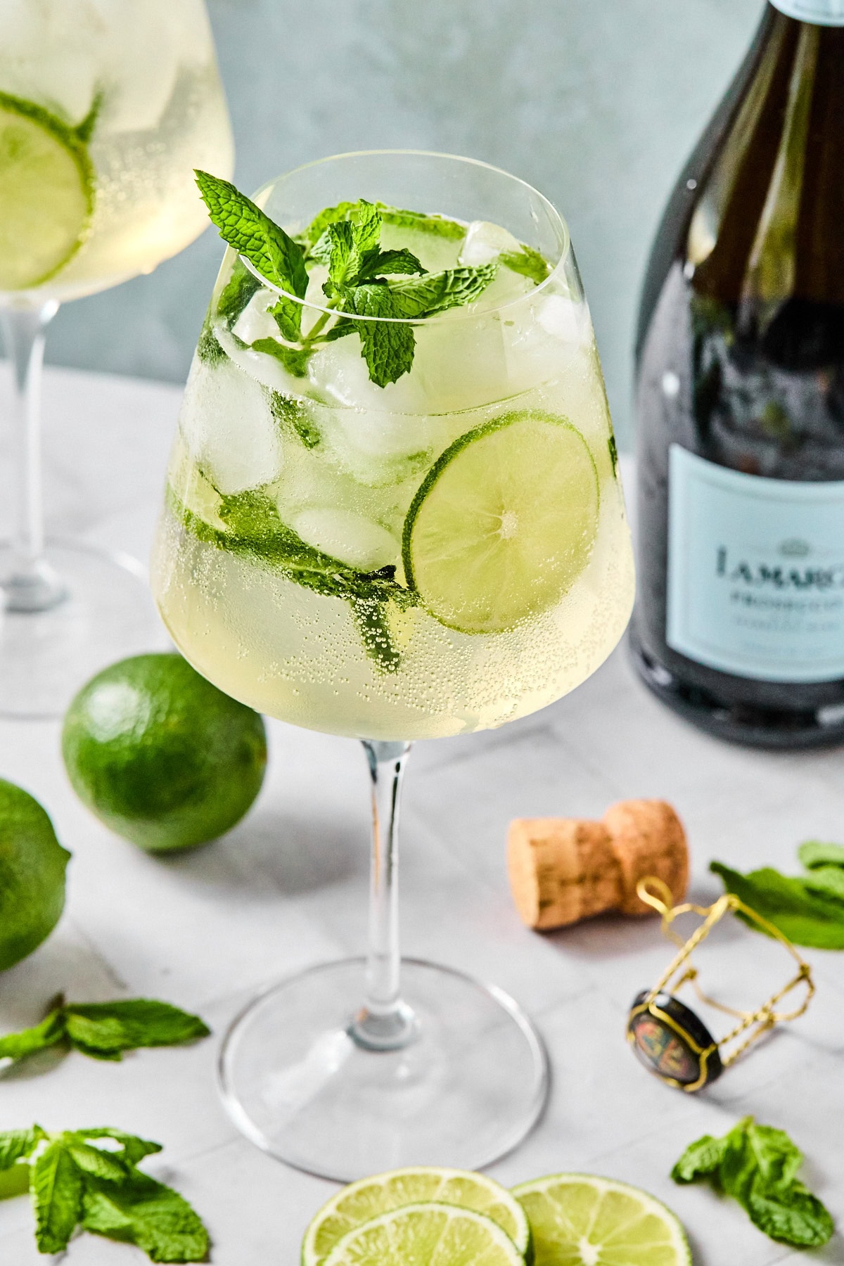 Close-up of a chilled Hugo Spritz with mint and lime, crisp bubbles visible in the glass.