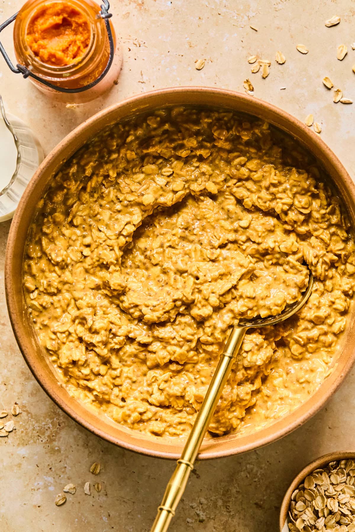 Mixing bowl with almond milk, pumpkin puree, Greek yogurt, protein powder, chia seeds, maple syrup, pumpkin pie spice, vanilla extract, and salt mixed together.