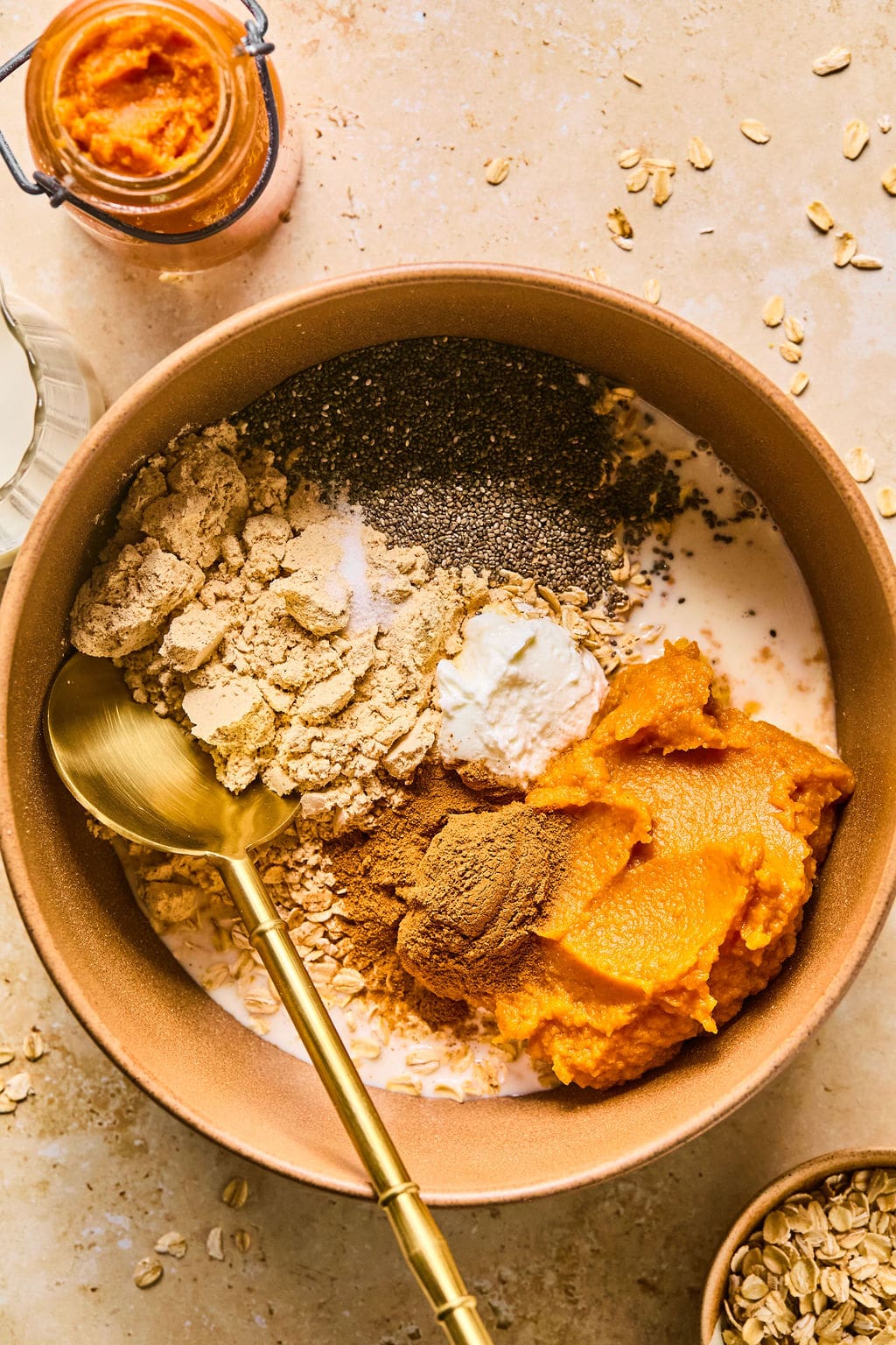 Mixing bowl with almond milk, pumpkin puree, Greek yogurt, protein powder, chia seeds, maple syrup, pumpkin pie spice, vanilla extract, and salt.