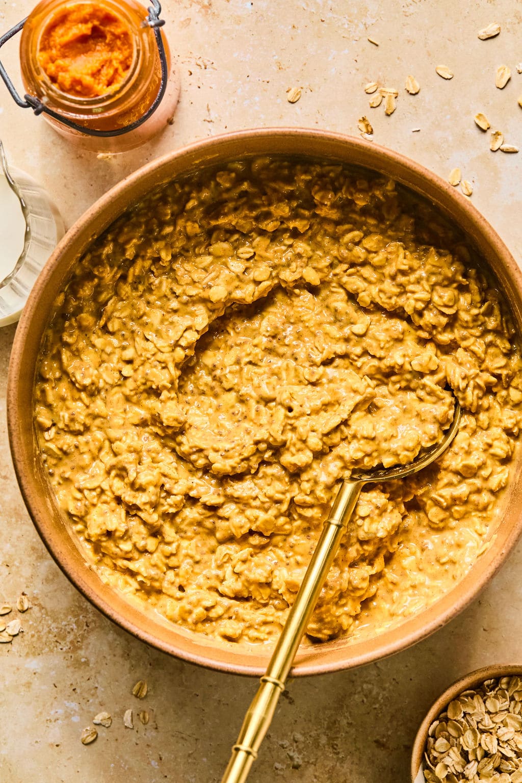 Mixing bowl with almond milk, pumpkin puree, Greek yogurt, protein powder, chia seeds, maple syrup, pumpkin pie spice, vanilla extract, and salt mixed together.