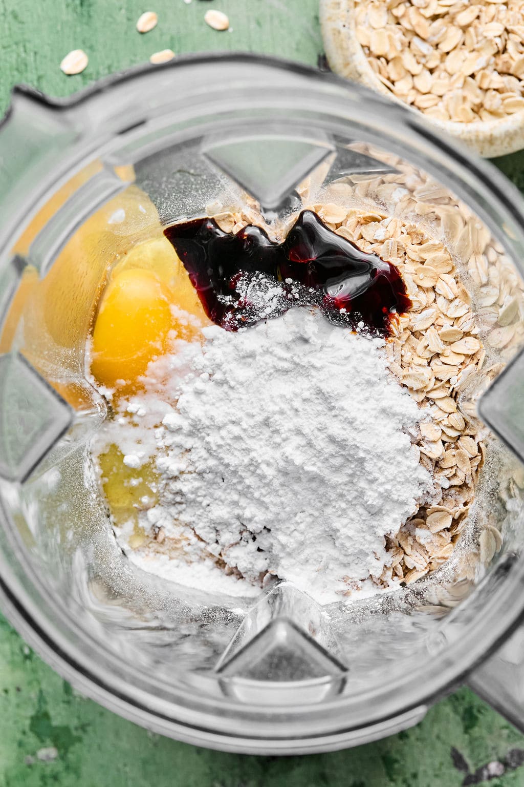 Oats, yogurt, almond milk, egg, vanilla, protein powder, baking powder, baking soda, powdered sugar, molasses, and salt in a high-speed blender.