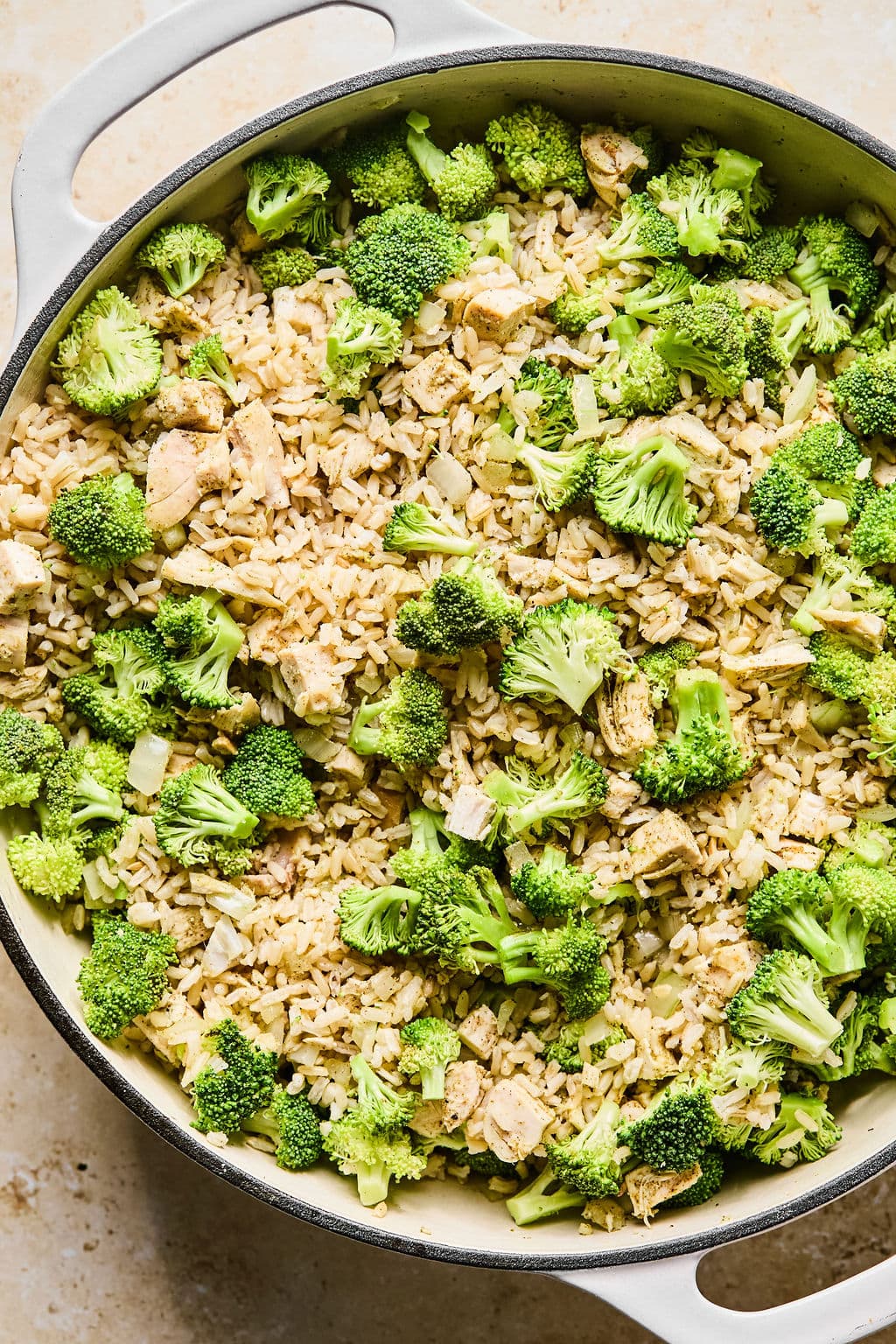 A large skillet with cooked rice and broccoli mixed into the turkey mixture for leftover turkey casserole. 