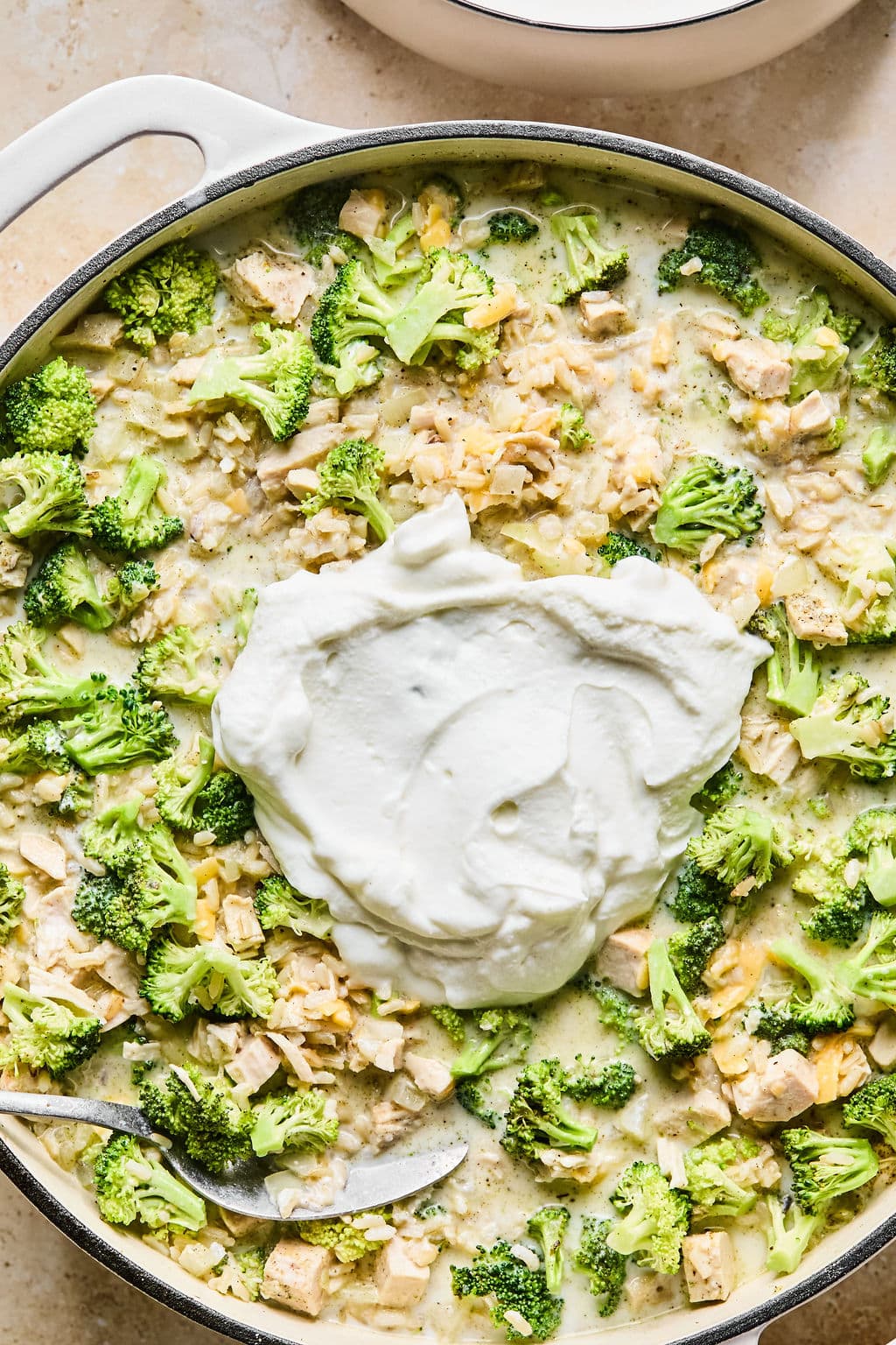Turkey casserole sauce poured over a turkey and rice mixture with a dollop of Greek yogurt on top, ready to be stirred for extra creaminess.
