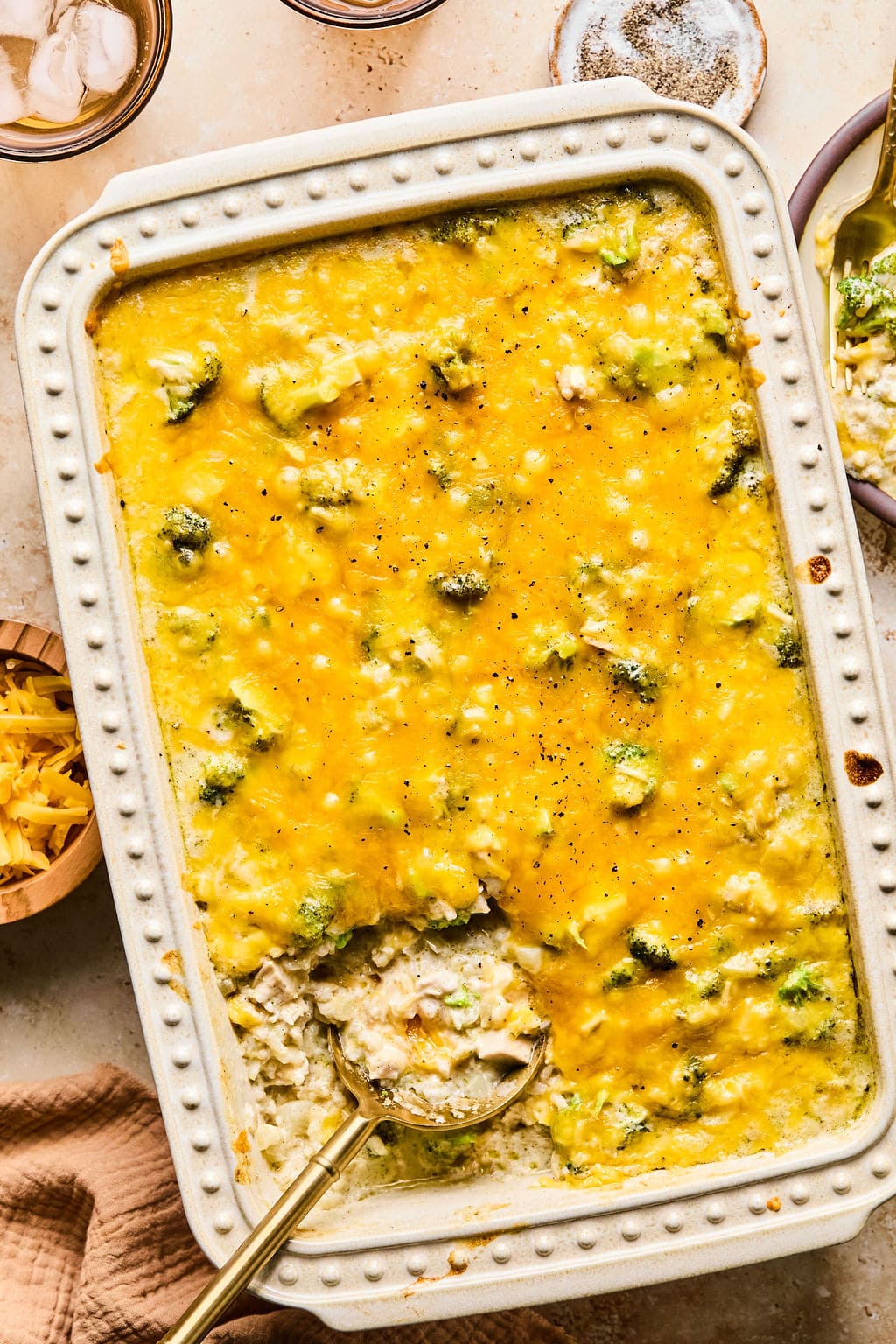 Leftover turkey casserole in a decorative serving dish with a gold spoon resting in the corner where a portion has been scooped out.