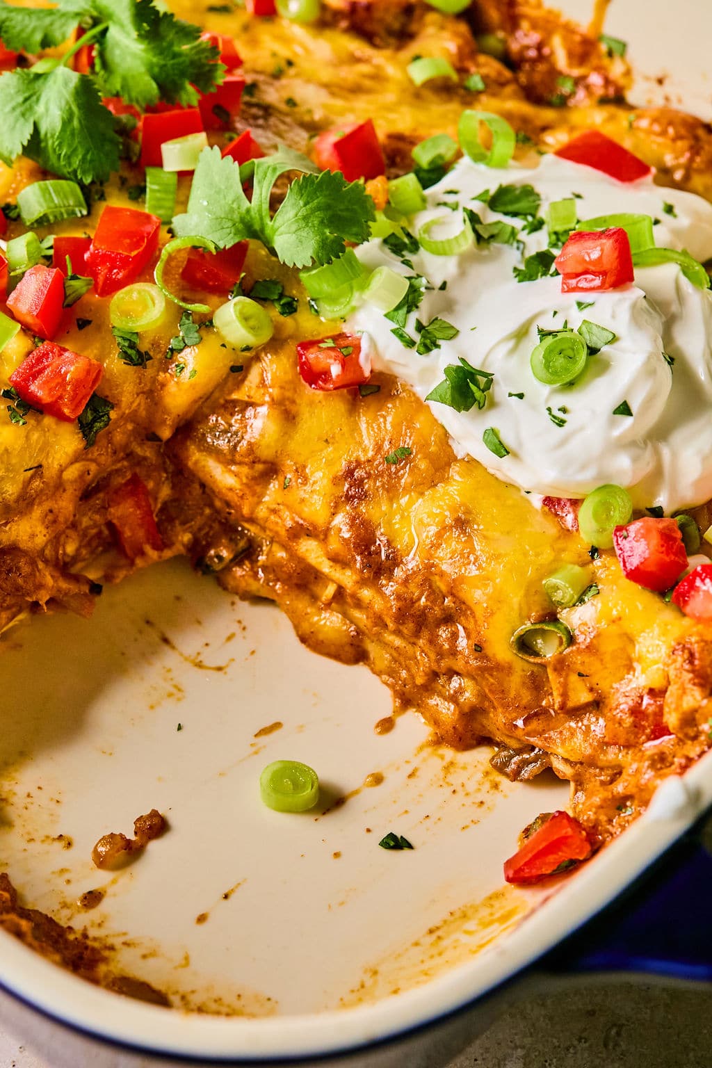 Close-up of leftover turkey enchilada casserole sliced and showing the layers of the turkey mixture, cheese, and tortillas.