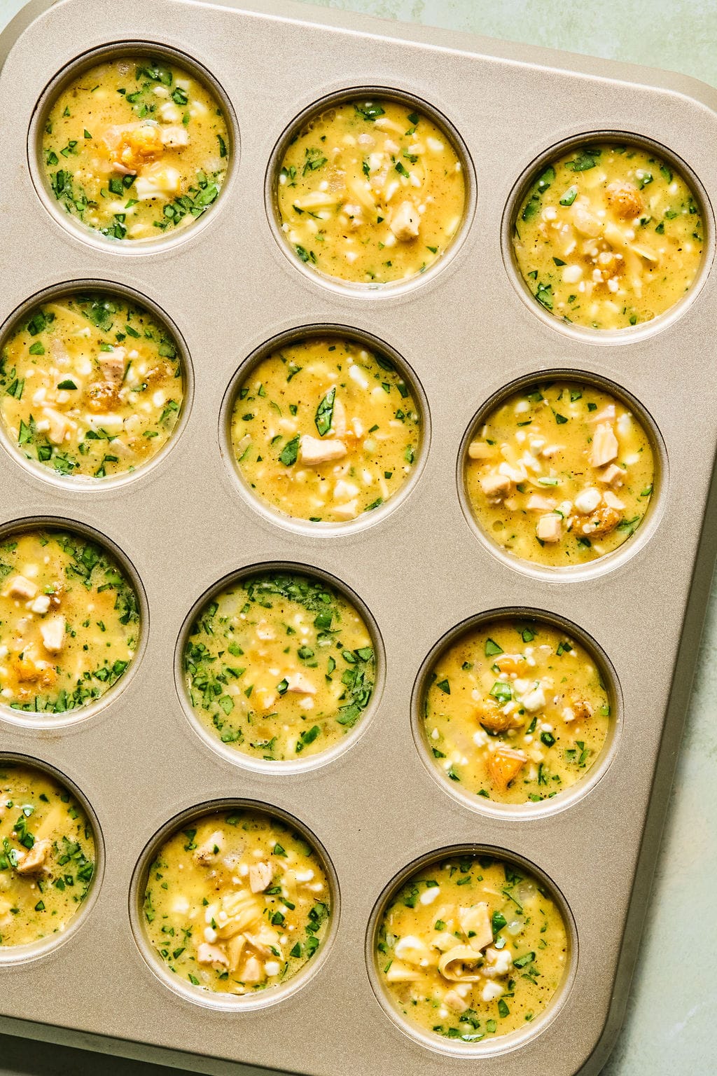 Thanksgiving frittata breakfast muffins divided among the muffin cups, ready to bake.