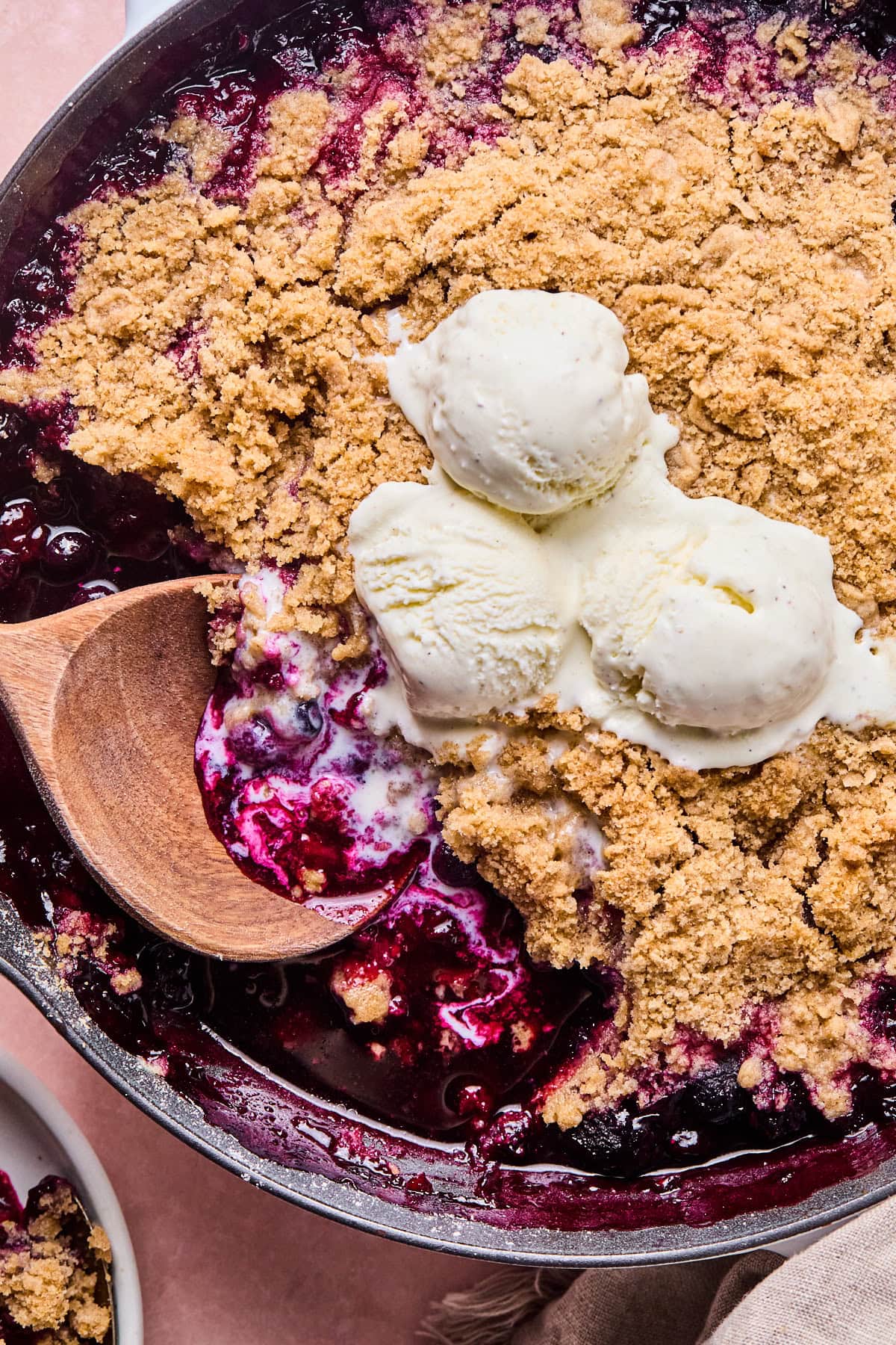 a close up of the crumble with melted vanilla ice cream