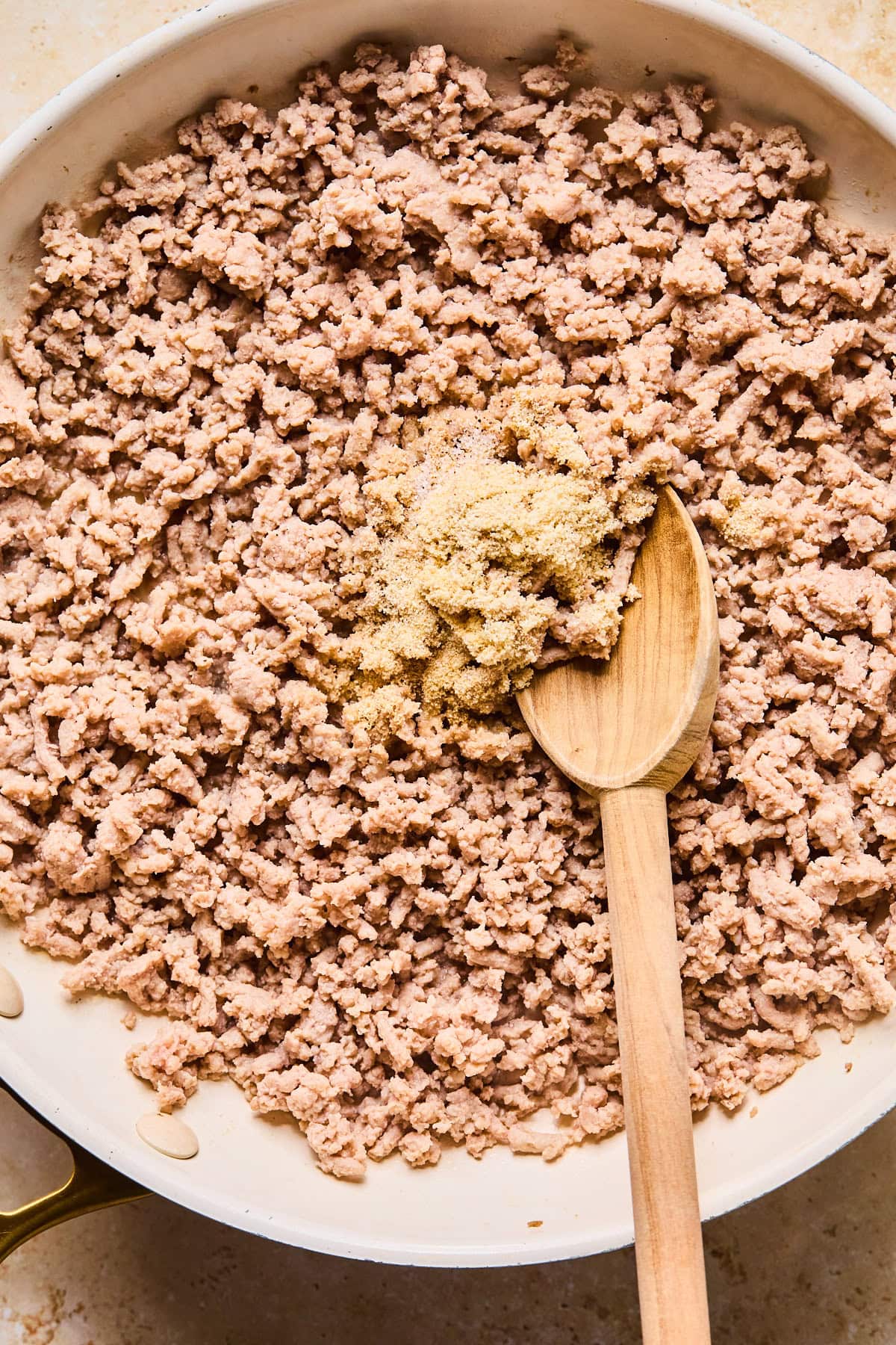 Ground turkey in a skillet broken up into pieces and seasoned with garlic powder, onion powder, salt, and pepper.