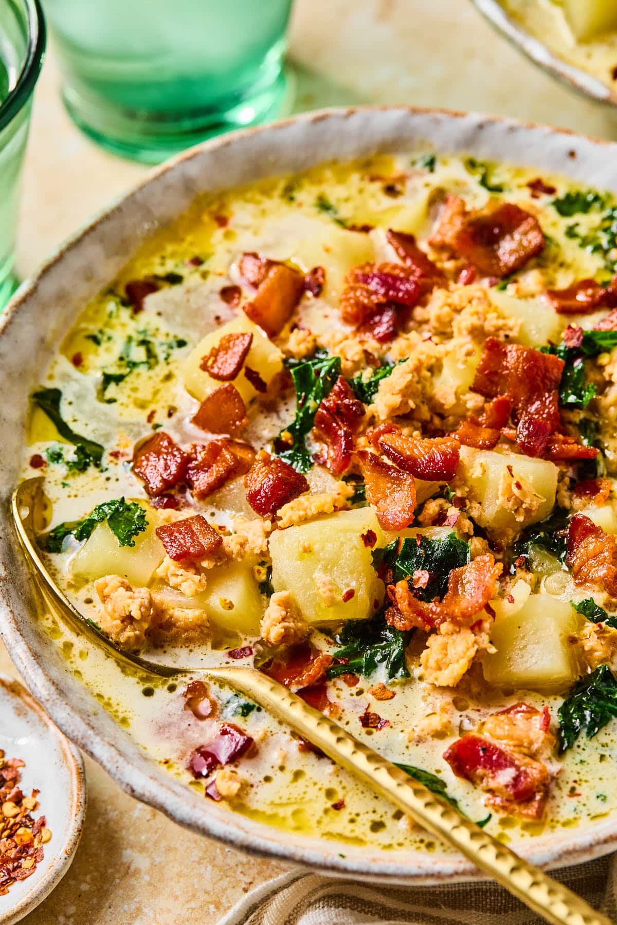 Close-up of a bowl of crockpot potato soup garnished with bacon bits.