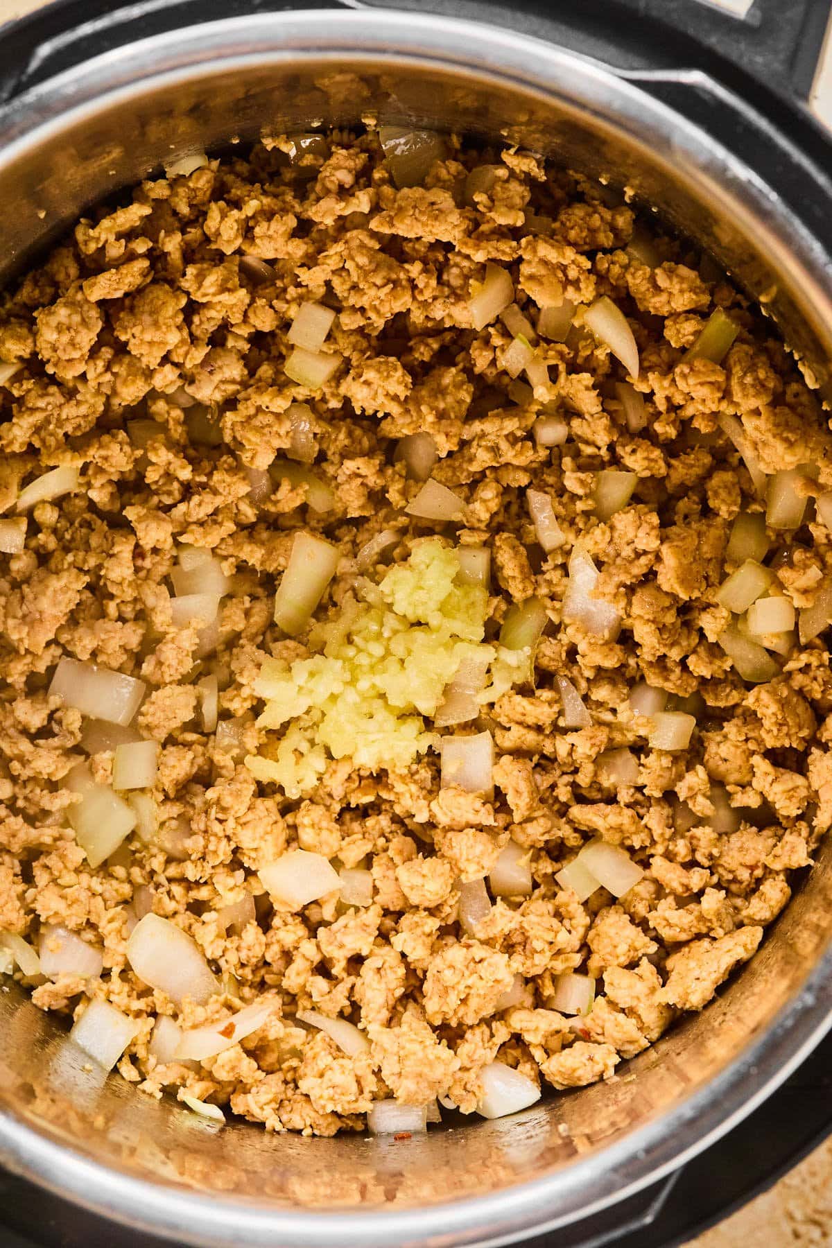 Italian sausage browning in the Instant Pot with diced onion and garlic.