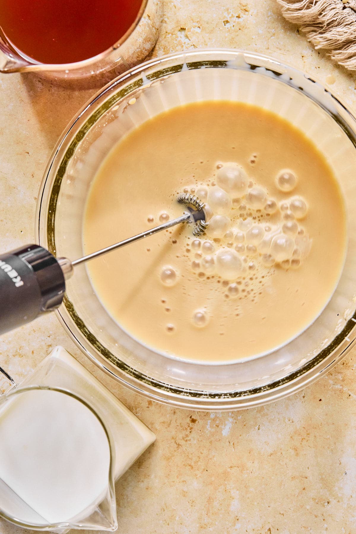 Chai concentrate and milk being frothed in a glass bowl.