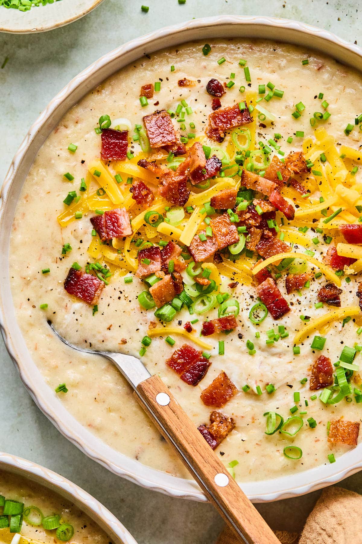 Close-up of a bowl of crockpot potato soup garnished with bacon bits.