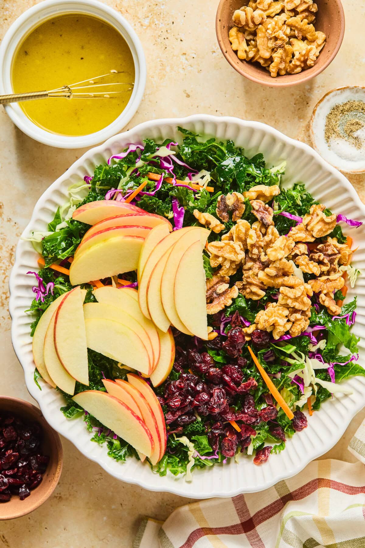 Apple slices, thinly sliced red onion, dried cranberries, and toasted walnuts added to the kale salad base.
