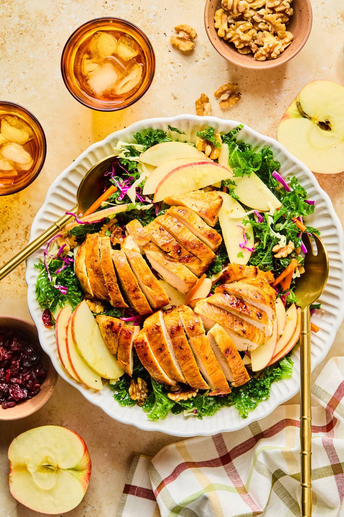 Winter kale salad in a large white serving bowl with gold serving spoons on either side.