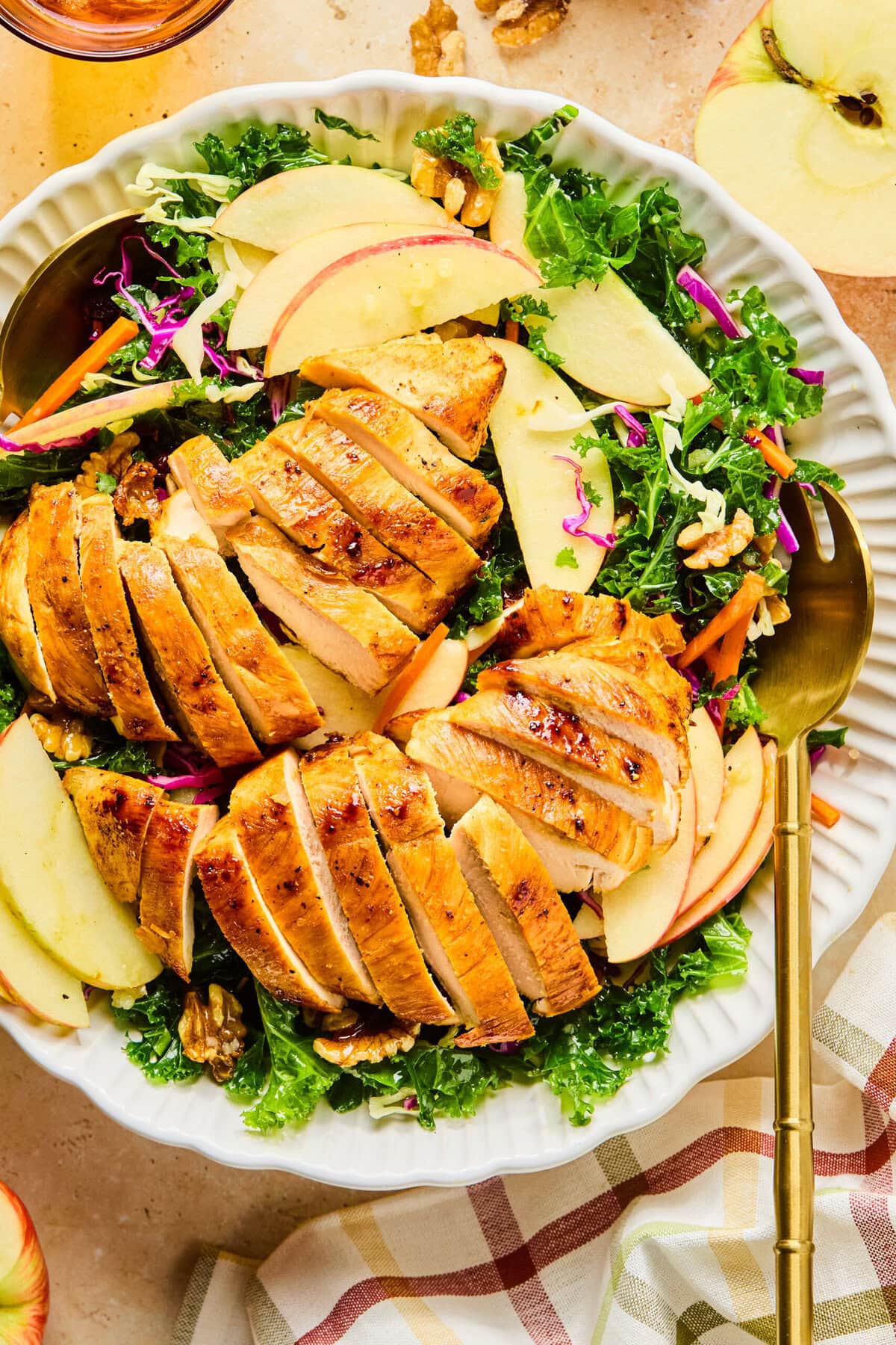 Winter kale salad in a large white serving bowl with gold serving spoons on either side.