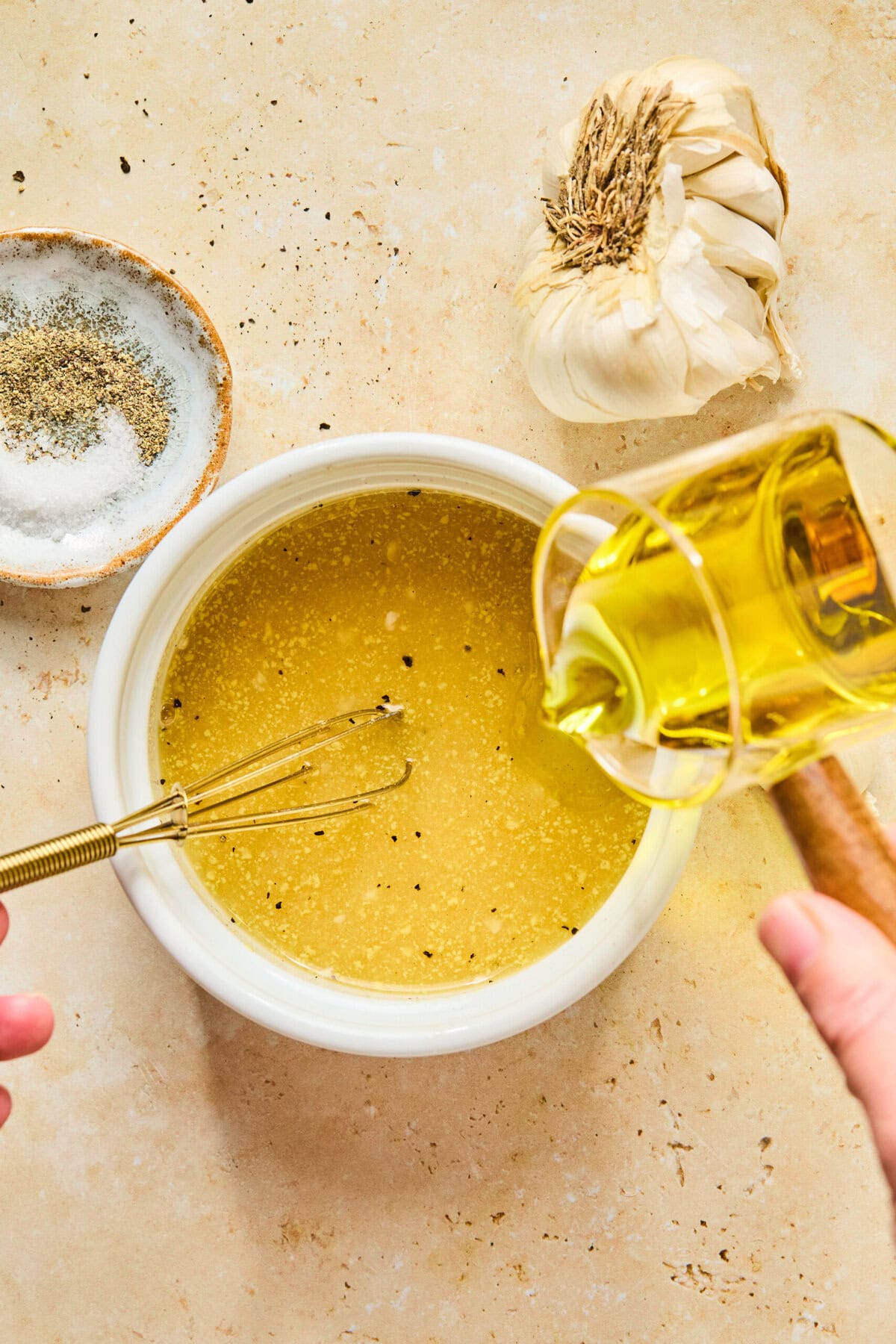 Champagne vinaigrette being whisked in a small bowl with Dijon mustard, maple syrup, garlic, salt, and pepper.