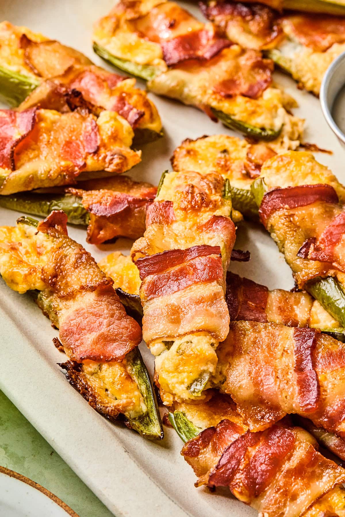 Close-up of crispy bacon wrapped jalapeno poppers showing creamy cheese filling.