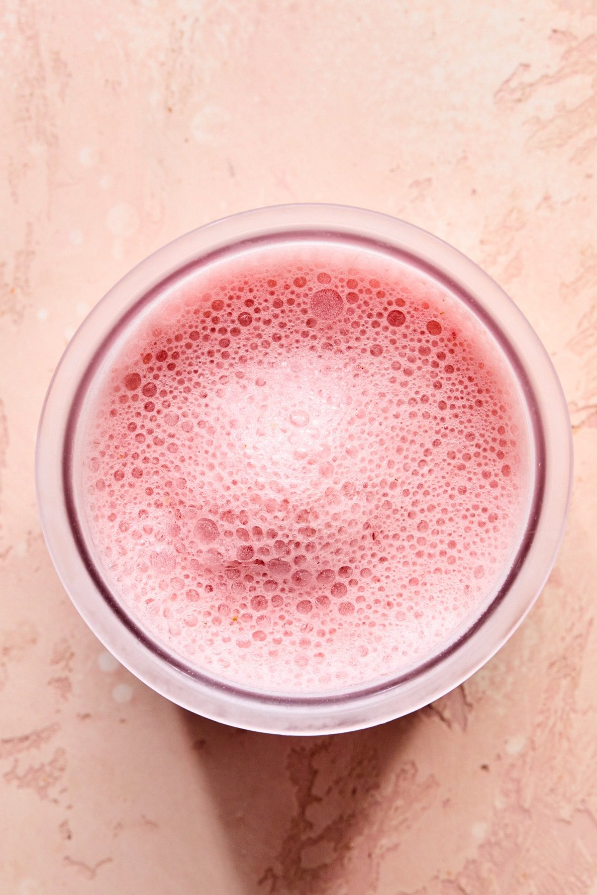Blended strawberry ice cream mixture in a Ninja Creami pint container.