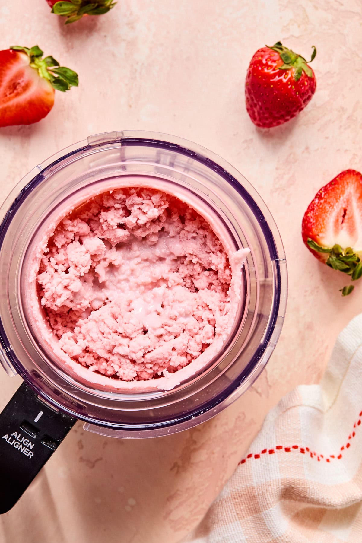 Frozen Ninja Creami pint placed in the machine; showing a blended mixture that is a little crumbly.