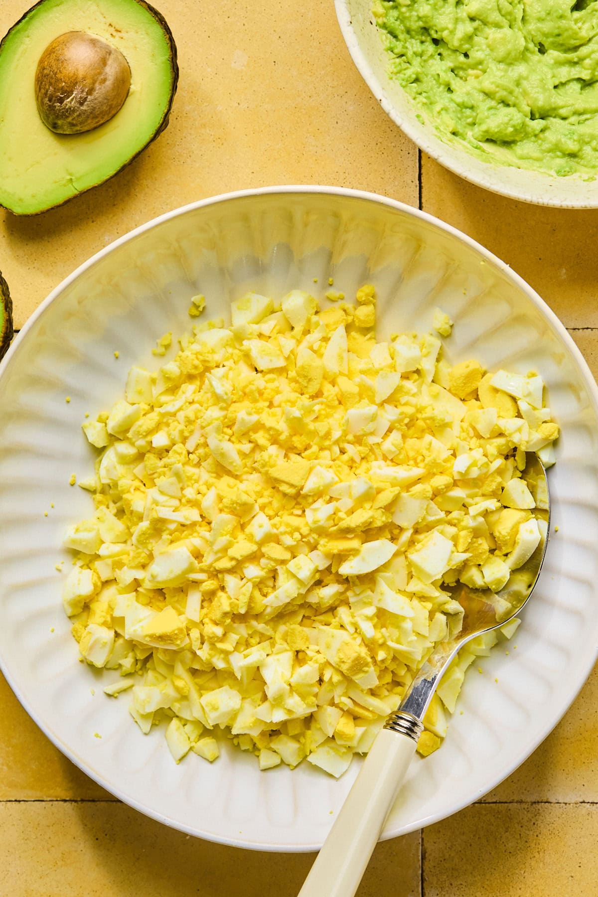Chopped hard-boiled eggs in a bowl with a serving spoon.