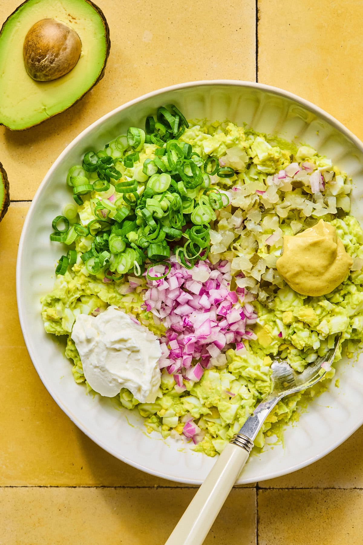 Chopped red onion, green onion, and dill pickles stirred into the avocado egg mixture with Dijon mustard and mayonnaise or Greek yogurt.