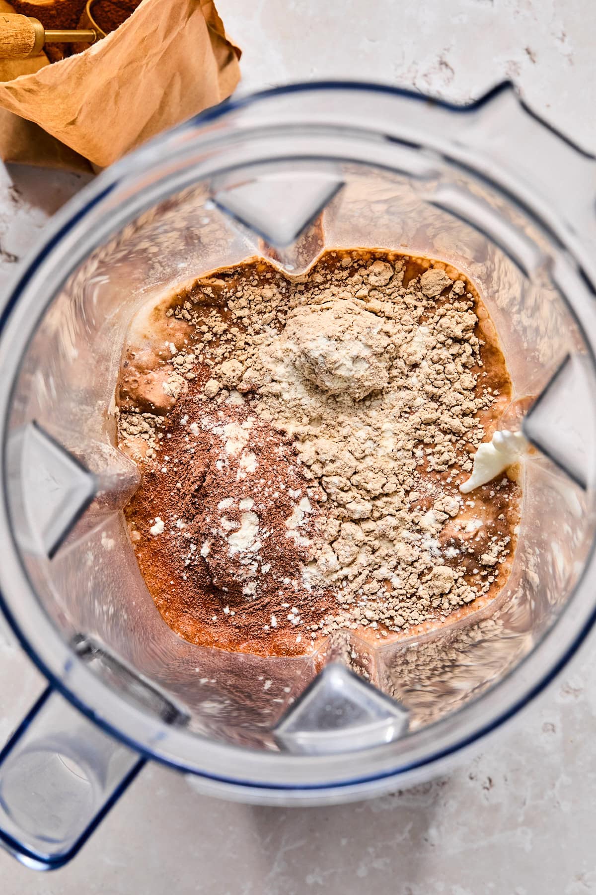 Ingredients for Ninja Creami chocolate ice cream added to Ninja Creami machine, with xanthan gum sprinkled evenly on top before blending.