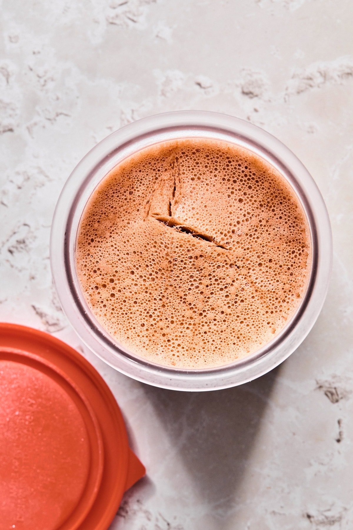 Frozen chocolate ice cream base in a Ninja Creami pint container.