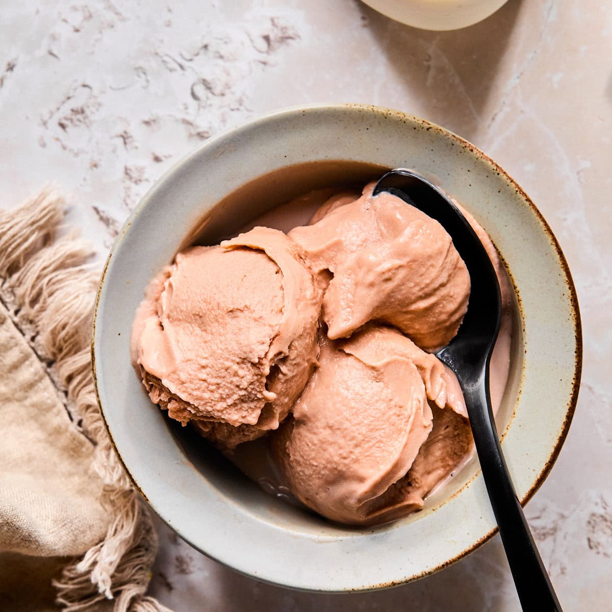 Bowl of Ninja Creami chocolate ice cream with a spoon scooping out a creamy bite.