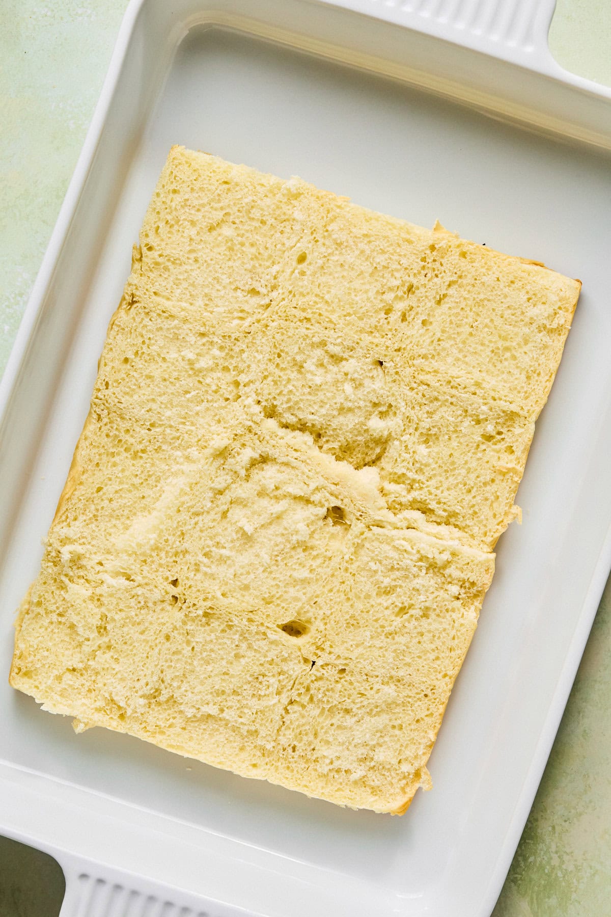 Hawaiian rolls sliced in half horizontally and placed in a baking dish.