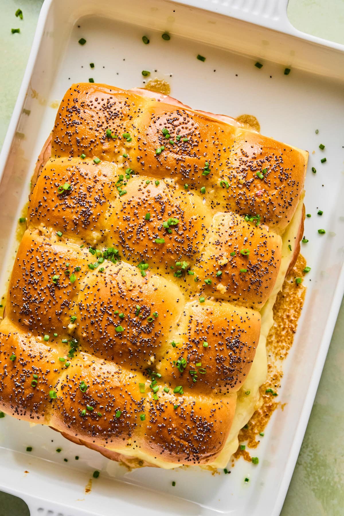 Baked ham and cheese sliders topped with chopped chives.