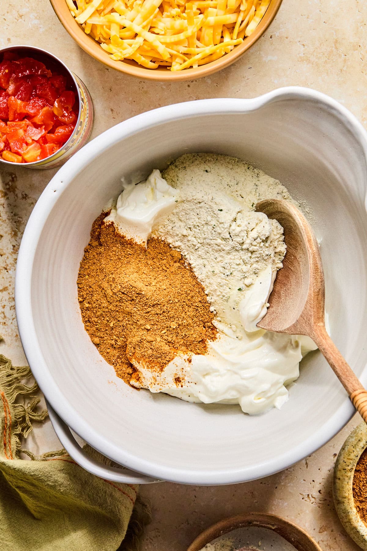 Sour cream with taco seasoning and ranch seasoning in a large bowl with a wooden spoon, ready to mix.