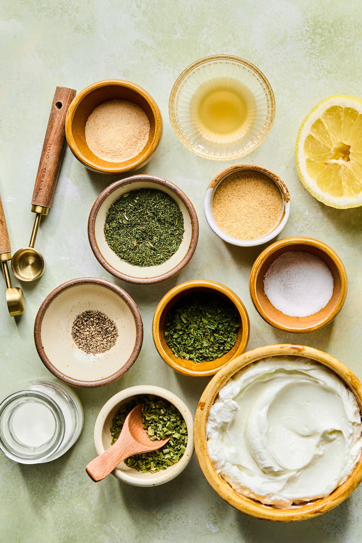 High protein ranch recipe ingredients laid out in small nesting bowls on a light green countertop.