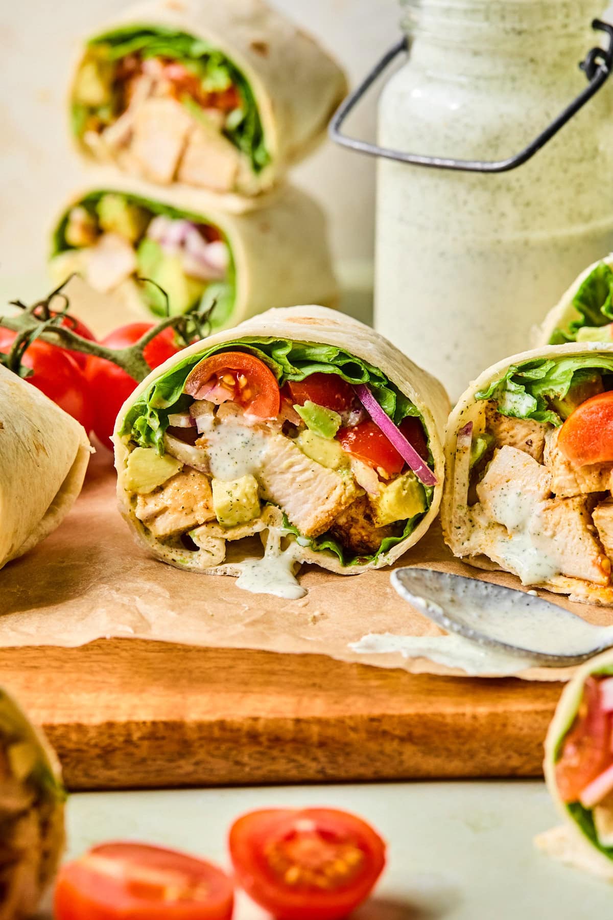 Close-up of a grilled chicken wrap cut in half with ranch dressing slightly dripping from the center.