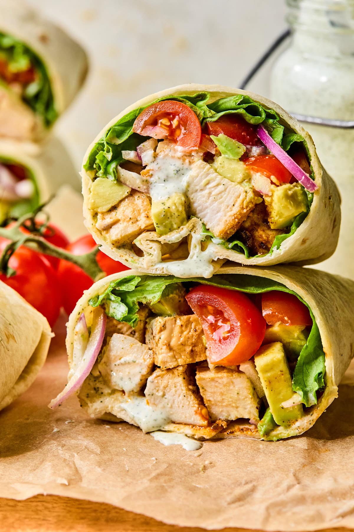 Close-up of two grilled chicken wraps stacked on top of each other, showing the layered ingredients inside.